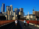 Women Jogging Across Stone Arch Bridge with City Skyline Beyond  Minneapolis  USA