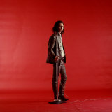 Rock Star Jim Morrison of the Doors Standing Alone Next to Microphone in Front of a Red Backdrop