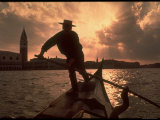 Gondolier  Against Sun and Cityscape  Standing on Front of Gondola Moving Away From Campanile