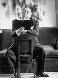 Actor Charles Laughton Reading Aloud From Book While Straddling a Chair