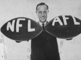 National Football League Commissioner Pete Rozelle Holding Together 2 Footballs Labeled NFL and Afl