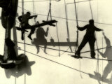 Silhouettes of Workers Using Rope Rigging to Clean and Paint the Side of a Ship