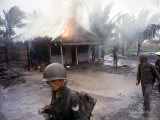 S Vietnamese infantrymen pass hut set fire after it was found Communist held during Vietnam War