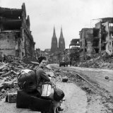 Homeless Refugee German Woman Sitting with All Her Worldly Possessions on Side of a Muddy Street
