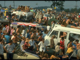Crowd of people  some Sitting on Top of Cars and Busses  During the Woodstock Music/Art Fair