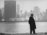 William J Zeckendorf walking alongside East River with the United Nations Building in background