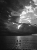 Natives Wading in Waning Light of Sunset That Permeates Thickening Clouds in the West Indies