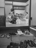 Guests Enjoying Meal in Japanese Tea House While Kneeling at Low Table with Shoes in Foreground