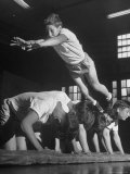 Corner of the Gym at a YMCA  a Boy Heads Into Somersault as He Jumps over Five of His Cohorts
