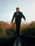Country Music Star Johnny Cash Walking Along Line of Railway Track with His Guitar