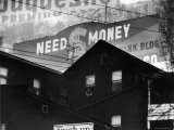 Loan Company's Need Money Sign Sardonically Looming over Slum Housing of the Unemployed