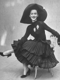 Model Showing Skirt Featuring Tiers of Ruffles Completed with Long Sleeved Top and Picture Hat