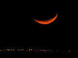 A Crescent Moon Dwarfs the Lights of Fort Riley Army Base in Central Kansas  January 22  2007