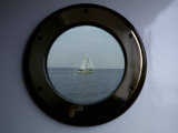 A Porthole Provides a Brass Frame for a Passing Sailboat