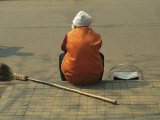 A Chinese Person Rests on a Street Curb after Sweeping the Sidewalk