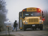 A Student Boards a School Bus in the Morning Fog
