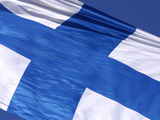 Close-up of the Flag of Finland on White Fabric with a Blue Cross Against Blue Sky