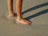 Feet in the Wet Sand of a Beach Wait for the Next Surge of Surf