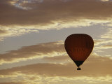 A Soaring Hot Air Balloon against a Cloud-Filled Sky at Dawn