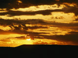 Clouds are Colored Shades of Orange by the Low Sun over 70 Mile Butte