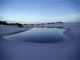 A White Sand Dune with a Pool of Water Reflecting the Sky