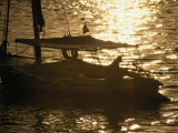 A Silhouetted-Fisherman on a Sailing Boat Looks out Towards the Setting Sun