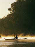 A Kayaker Paddles Through the Mist in the Low Sunlight