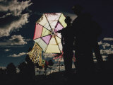 Several Men Hold a Kite That is Backlit by the Sun