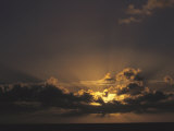 Rays of Sunlight Beam from Behind a Cloud at Sunset over Water