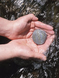 Person Holding Rock with the Word Blessings in Rushing Water