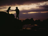 A Man with a Camera Helps a Woman Down Rocks Near Tanah Lot Temple