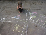 A Young Girl Admires a Drawing That She Did with Sidewalk Chalk