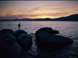 A Man Walks Along Large Rocks Jutting out into the Harbor