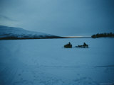 Night View of a Snowmobile Pulling a Sled Across the Lake