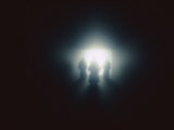 The Silhouette of Three Figures Dressed in Robes Standing Before a Bright Light