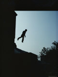 Silhouette of a Boy Jumping Between Rooftops of Abandoned Buildings