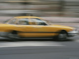 A Yellow Taxi Rushes by on a Busy New York Street