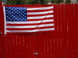 A United States Flag Hangs on a Bright Red Fence
