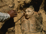 An Archeologist Brushes Dirt from the Mummy of a Child