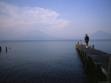A Hiker with Backpack Walks out on a Pier on a Mountain Lake