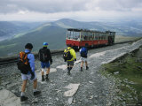 A Train Filled with Tourists Passes Hikers Descending Mount Snowdon