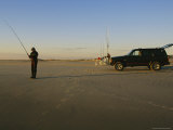 A Man Holds a Fishing Pole While Standing Near His Jeep Truck