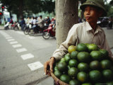 An Orange Vendor Smokes a Cigarette as He Waits for Customers