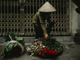 A Woman in a Conical Hat with Bundles of Flowers and Roses to be Sold