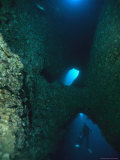 Diver Swimming Around Crevasses in a Reef Wall