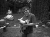 A Young Boy Holds a Chicken in His Backyard in Nebraska