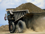 A Dump Truck Carrying Gravel Kicks up a Cloud of Dust