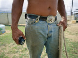 A Close View of a Man in Jeans with a Large Belt Buckle Holding a Rope