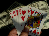Hand Holding a Straight Flush in Front of Several Hundred Dollar Bills