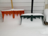 Two Snow Covered Shovels on a Porch